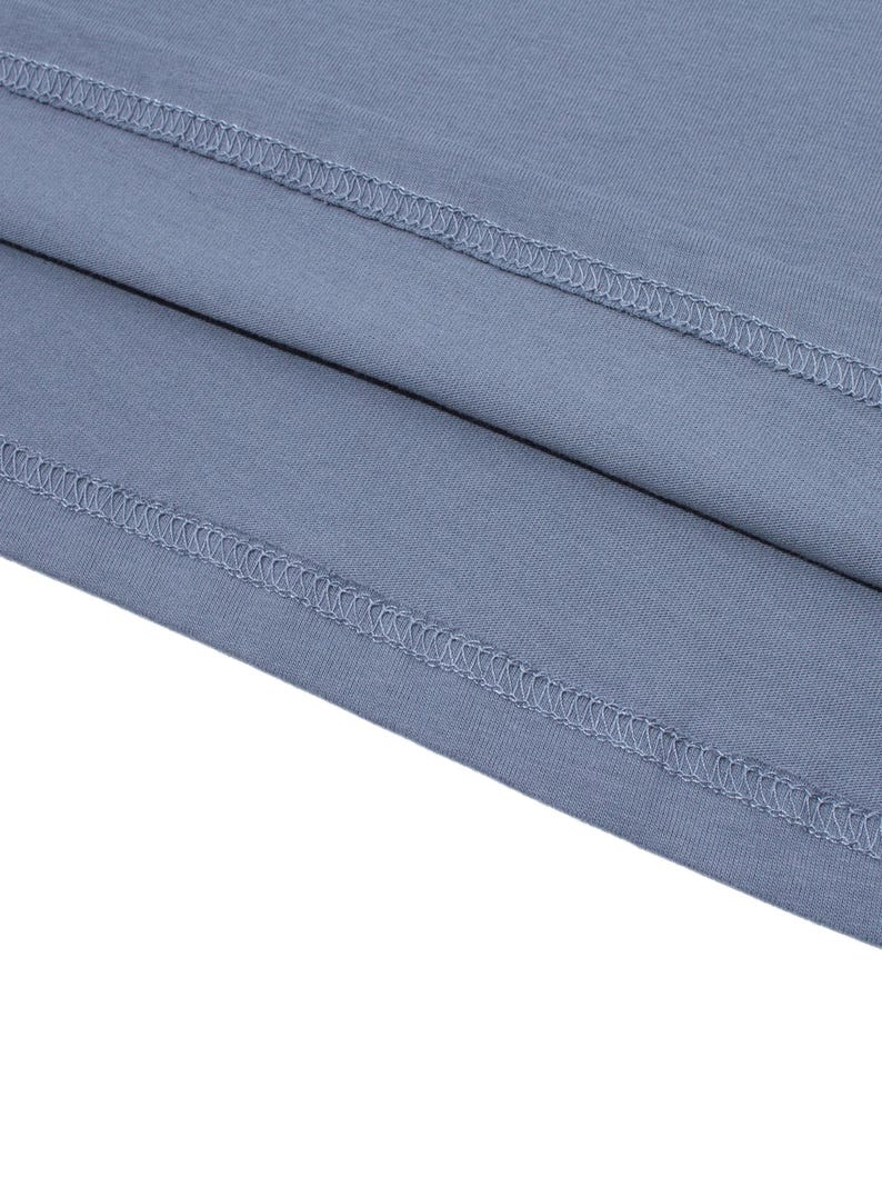 Detailed shot of the double-stitched hem and fabric layers of a blue-grey t-shirt.
