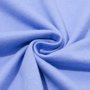 May include: Close-up of a light blue fabric with a soft, textured appearance. The fabric is tightly woven, with visible vertical and horizontal lines. The material is gathered and folded, creating a swirling pattern.