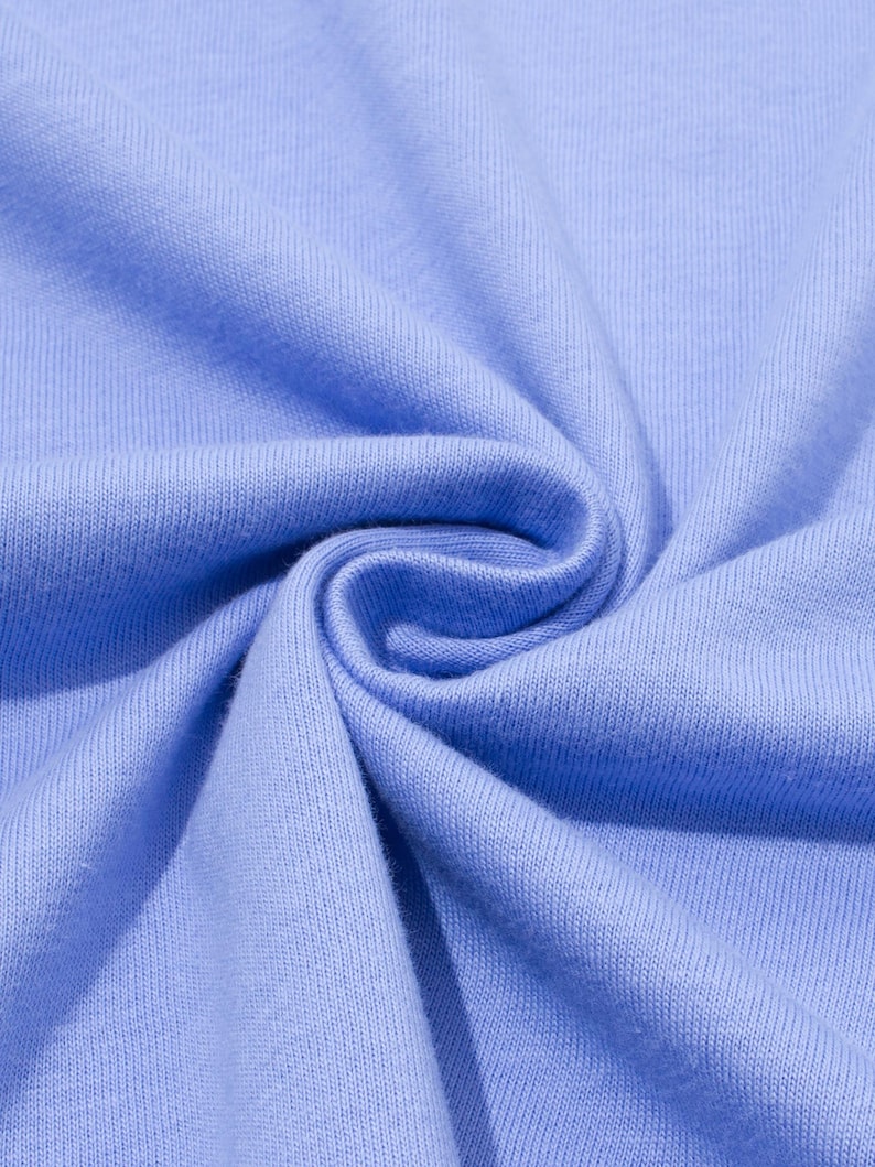 May include: Close-up of a light blue fabric with a soft, textured appearance. The fabric is tightly woven, with visible vertical and horizontal lines. The material is gathered and folded, creating a swirling pattern.