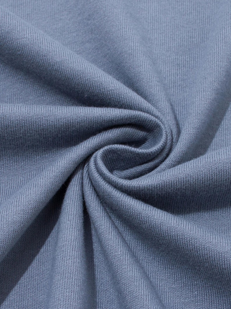 Close-up view of swirled blue-gray cotton knit fabric showing texture and weave.