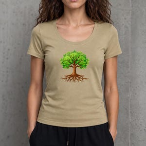 May include: A tan scoop-neck t-shirt featuring a vibrant tree graphic. The tree has a brown trunk, roots, and bright green leaves. The shirt is a neutral color and has short sleeves.