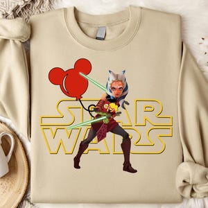 Star Wars shirt featuring fan-favorite characters like Darth Vader, Baby Yoda, Chewbacca, and Han Solo with fun Mickey head accents. This soft, unisex tee or sweatshirt is perfect for Disney trips, Star Wars Day, or matching family outfits. A playful mix of galaxy and Disney magic, ideal for park hopping, themed parties, or gifting to fans of the Mandalorian and the whole Star Wars crew.