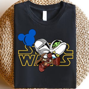 Star Wars shirt featuring fan-favorite characters like Darth Vader, Baby Yoda, Chewbacca, and Han Solo with fun Mickey head accents. This soft, unisex tee or sweatshirt is perfect for Disney trips, Star Wars Day, or matching family outfits. A playful mix of galaxy and Disney magic, ideal for park hopping, themed parties, or gifting to fans of the Mandalorian and the whole Star Wars crew.