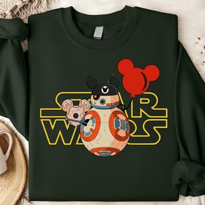 Star Wars shirt featuring fan-favorite characters like Darth Vader, Baby Yoda, Chewbacca, and Han Solo with fun Mickey head accents. This soft, unisex tee or sweatshirt is perfect for Disney trips, Star Wars Day, or matching family outfits. A playful mix of galaxy and Disney magic, ideal for park hopping, themed parties, or gifting to fans of the Mandalorian and the whole Star Wars crew.