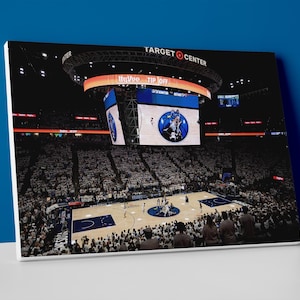 May include: A canvas print of a basketball game in progress at the Target Center. The arena is filled with spectators. The scoreboard displays the words "Tip Off" and the arena's name. The court is visible with players in action.