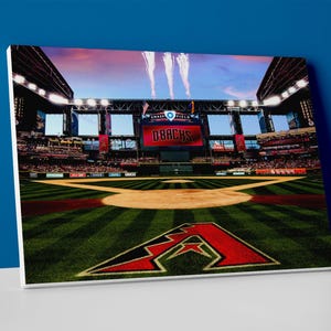 May include: A baseball field with green grass and a red and white Arizona Diamondbacks logo in the centre. The scoreboard in the background reads "D-backs".