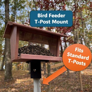 May include: A wooden bird feeder with a T-post mount, filled with birdseed. The feeder is brown with a black metal bracket, designed to fit standard T-posts. Text on the image reads "Bird Feeder T-Post Mount" and "Fits Standard T-Posts."