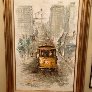 May include: A framed oil painting depicting a yellow cable car traveling up a steep hill in a city. The painting features buildings, a bridge, and trees in the background. The cable car has a sign that reads "California Street Cable Railroad".