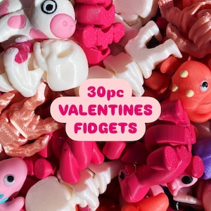 May include: A collection of 30 Valentine's Day themed fidget toys in various colors, including pink, red, white, and orange. The toys are made of plastic and have different shapes, such as hearts, unicorns, and ladybugs. The text "30pc VALENTINES FIDGETS" is displayed on the image.
