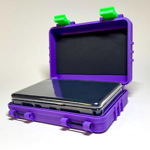 May include: Purple protective case with a black interior and a phone inside. The case has green latches and is open, revealing the phone. The case is designed to protect the phone from damage.