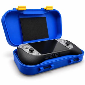 May include: A handheld gaming console with a clear transparent casing and black ergonomic grips, resting inside a bright blue protective hard-shell carrying case. The case features yellow latches and a black foam insert on the interior lid.