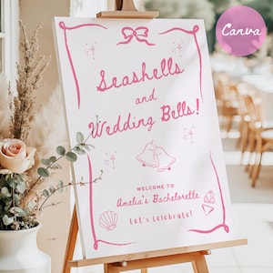 Könnte beinhalten: Ein weißes Schild mit rosa Schriftzug, auf dem "Seashells and Wedding Bells!" steht. Willkommen zum Junggesellinnenabschied von Amelia! Lasst uns feiern! Das Schild steht auf einem Holzständer.