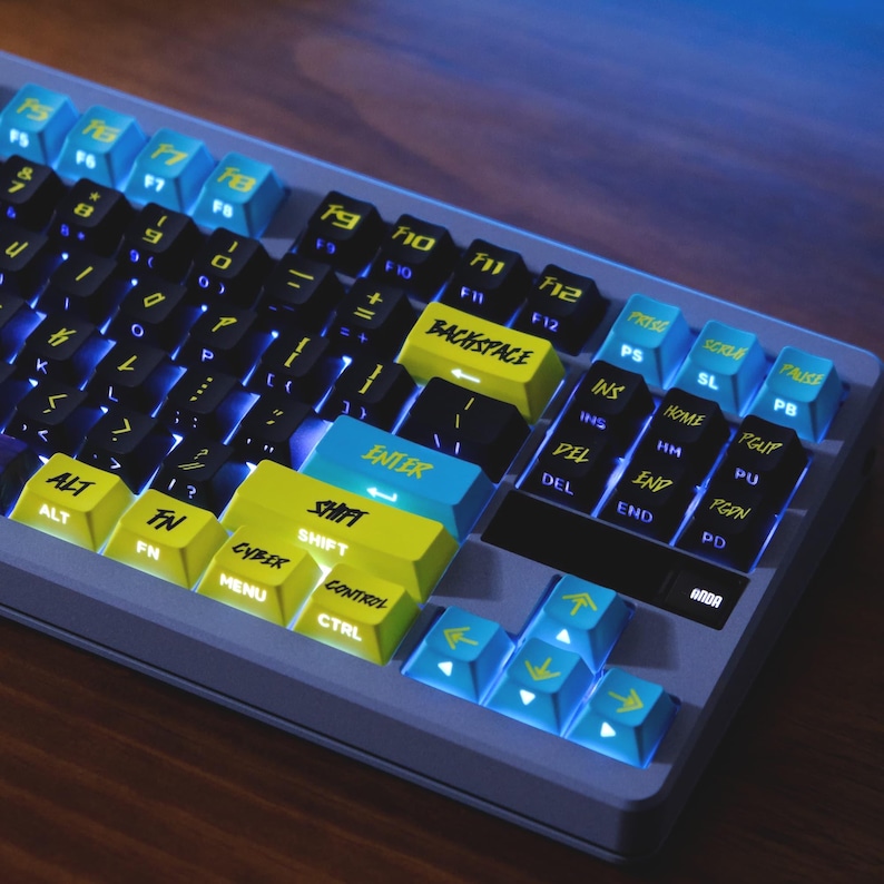 May include: A mechanical keyboard with a gray frame and a variety of colorful keycaps. The keys are black, yellow, and blue, with white lettering. The keyboard has a backlight, and the keys are arranged in a standard layout.