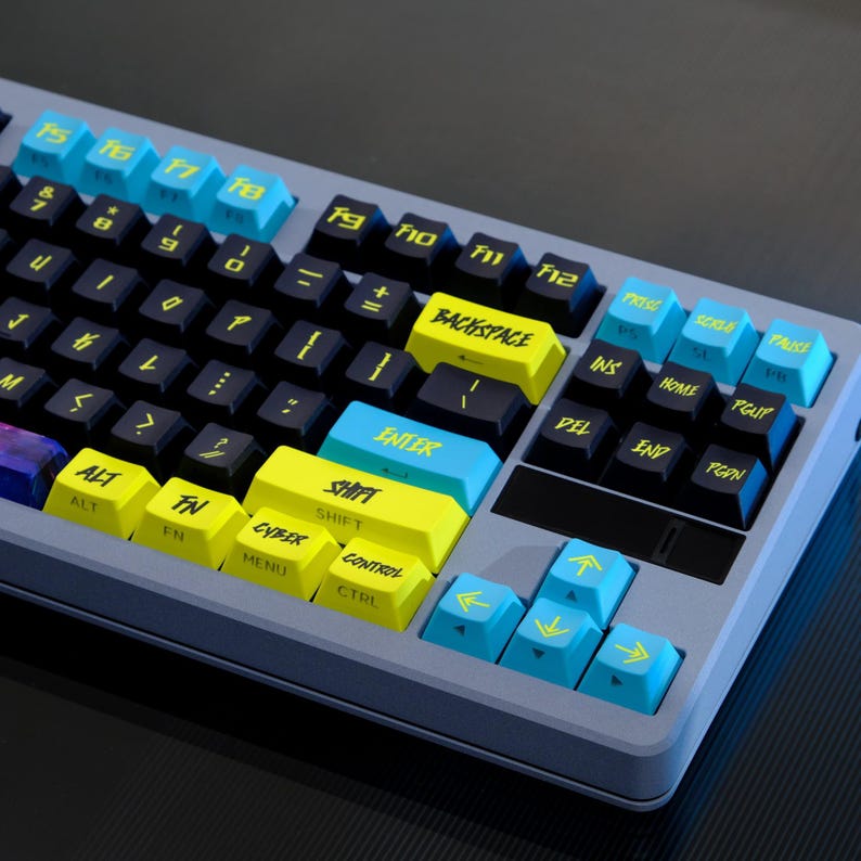 May include: A mechanical keyboard with a gray frame and black keys. The keyboard features blue and yellow accent keys with labels like "ENTER", "SHIFT", and function keys. The keycaps have a unique font.