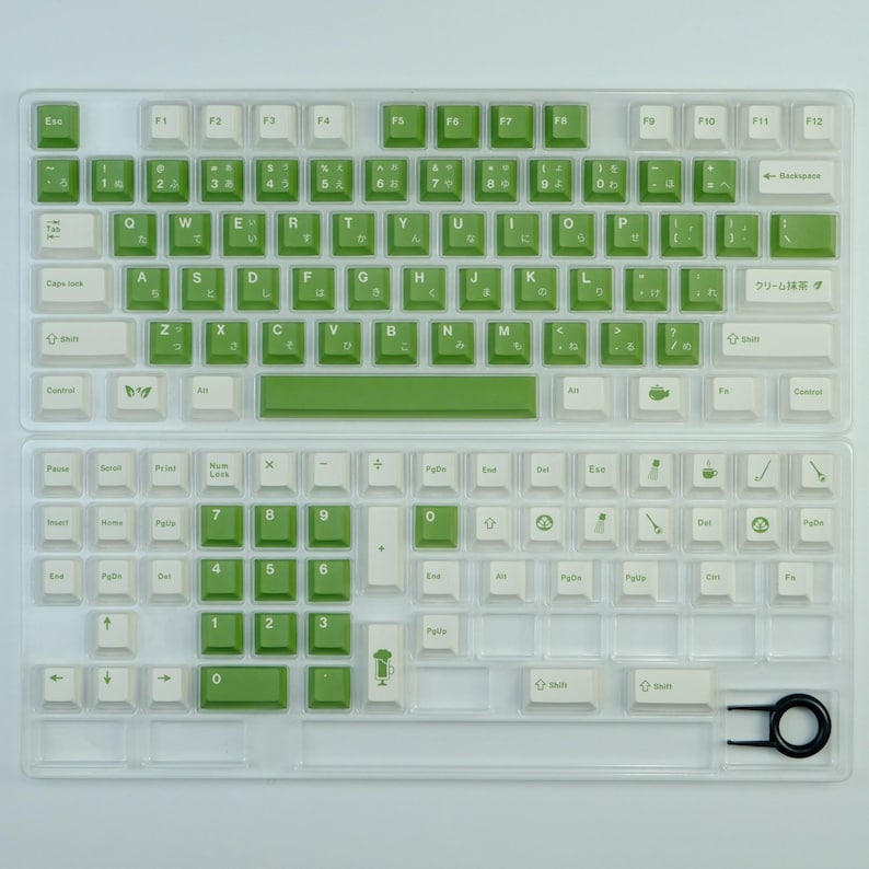 May include: A mechanical keyboard with white and green keycaps. The keycaps have Japanese characters and English letters. The keyboard is in a clear plastic case. A keycap puller is included.