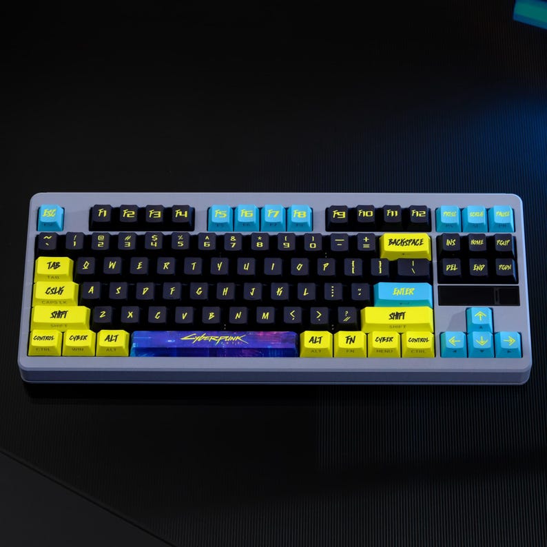 May include: A gray mechanical keyboard with black keys and yellow and blue accents. The keyboard has the word "Cyberpunk" on the spacebar. The keys are labeled with white letters and symbols.