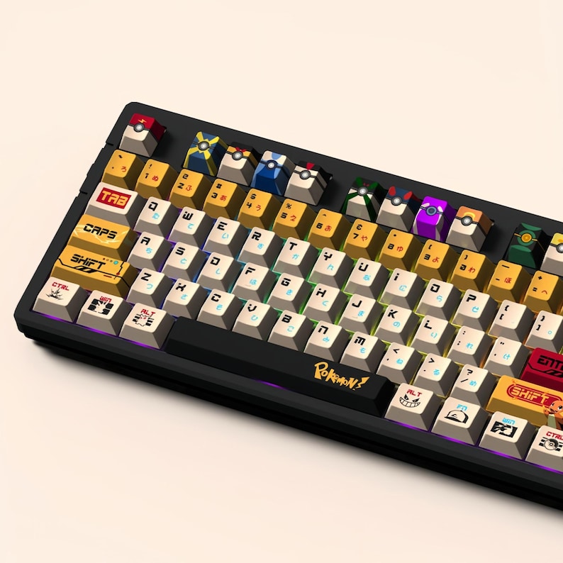 Puede incluir: Un teclado mec&aacute;nico negro con teclas personalizadas que representan personajes de Pok&eacute;mon. Las teclas son amarillas, rojas, azules, verdes y moradas. El teclado tiene un marco negro y una barra espaciadora negra con el texto "POKEMON!" impreso en ella.