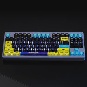 May include: A gray mechanical keyboard with black, yellow, and blue keycaps. The keyboard has a cyberpunk theme, with the word "Cyberpunk" printed on the spacebar. The keys are backlit with blue lights.