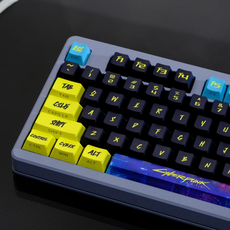 May include: A close-up of a mechanical keyboard with black keys and yellow and blue accent keys. The keyboard has the word "Cyberpunk" printed on the spacebar. The keys are labeled with white and yellow text.