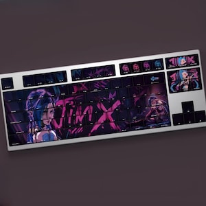 May include: A white mechanical keyboard with custom keycaps featuring a purple and pink graphic design. The design includes the word "Jinx" and an illustration of a character with blue hair. The keyboard has a full layout with a number pad.