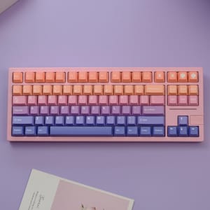 May include: A pastel-colored mechanical keyboard with a gradient design. The keycaps transition from peach to pink, purple, and blue. The keyboard has a pink frame and a standard QWERTY layout.