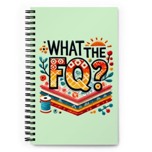 Puede incluir: Una libreta espiral verde con el texto "WHAT THE FQ?" en letras de colores. Las letras están rodeadas por una pila de cuadrados de tela de colores, una bobina de hilo y diseños florales.
