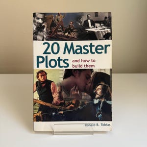 Op de afbeelding: Een boek getiteld "20 Master Plots and how to build them" met een collage van afbeeldingen op de omslag. De omslag toont een man op een boot, een kussend stel en andere scènes. De naam van de auteur, Ronald B. Tobias, staat onderaan.