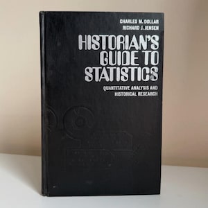 May include: A black hardcover book titled Historian's Guide to Statistics: Quantitative Analysis and Historical Research by Charles M. Dollar and Richard J. Jensen, featuring silver text and a subtle embossed circular graphic design.