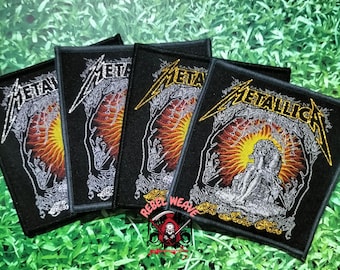 May include: A set of four rectangular embroidered patches featuring the Metallica logo in yellow and white thread. The design includes a central figure sitting on a rock against a sunburst background with orange and yellow rays, all on a black fabric.