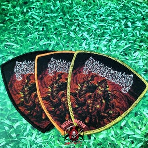 May include: Three shield-shaped embroidered patches featuring a black background with a red and orange fiery graphic and the white text Dissection. Each patch has a distinct border color: black, orange, and yellow, with a small logo at the bottom.