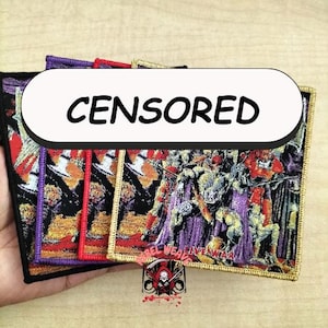 May include: Embroidered patches with a detailed, colourful design featuring figures in purple, orange, and black. The patches have a gold border and the word "CENSORED" in bold black letters. The patches are held in a hand.