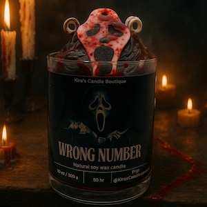 Könnte beinhalten: Sojawachskerze in einem Glas mit Horror-Thema. Die Kerze ist mit einem rot-weißen Maskenmotiv verziert. Das Glas hat ein schwarzes Etikett mit den Worten "WRONG NUMBER" und einer Geistergesichtsgrafik. Die Kerze wiegt 300 g.