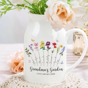 May include: Two white ceramic mugs with handles. The mugs are decorated with a floral design and the text "Grandma's Garden Love Grows Here".