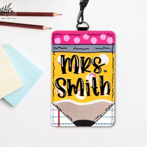 K&ouml;nnte beinhalten: Ein gelber, stiftf&ouml;rmiger Ausweishalter mit dem Text "MRS. SMITH" in Schwarz. Die Oberseite hat ein rosa Tupfenmuster und die Unterseite ein Bleistiftspitzen-Design. Enth&auml;lt ein schwarzes Schl&uuml;sselband und befindet sich neben Bleistiften und Haftnotizen.