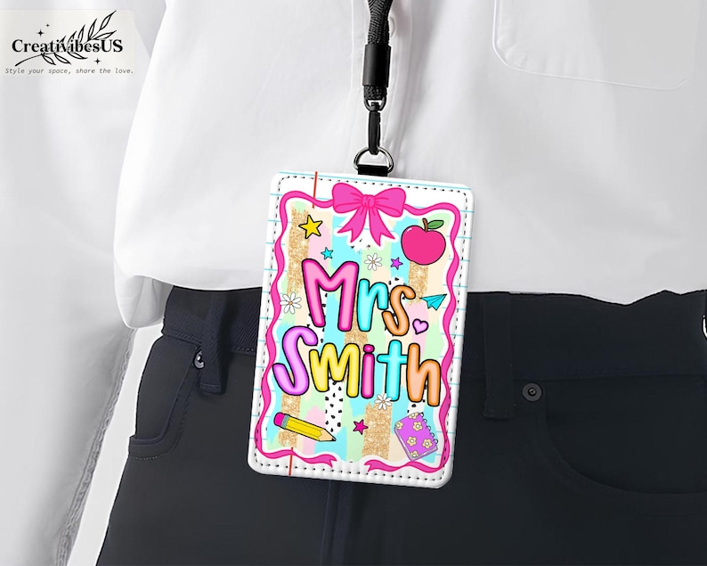 May include: A colorful teacher ID badge with the name "Mrs. Smith" in bubble letters. The badge features a pink bow, apple, pencil, and stars on a striped background. It is hanging from a black lanyard.