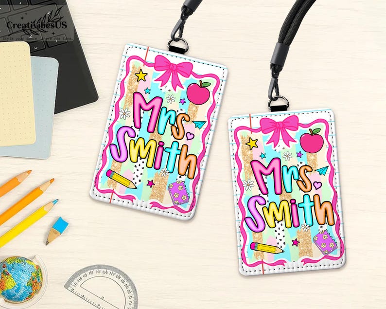 May include: Two personalized teacher ID badges with the name "Mrs. Smith" in colorful bubble letters. Each badge features a pink bow, apple, stars, and pencil design. The badges are attached to black lanyards.