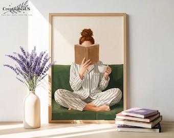 Puede incluir: Una impresión artística enmarcada representa a una persona en pijama a rayas leyendo un libro y sosteniendo una taza, sentada en un sofá verde. También se ve un jarrón con lavanda y una pila de libros. La obra de arte está en una habitación de tonos claros.
