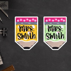 K&ouml;nnte beinhalten: Zwei bleistiftf&ouml;rmige Aufkleber, einer gelb und einer gr&uuml;n, beide mit dem Namen "Mrs. Smith" in schwarzer Schrift. Der gelbe Bleistift hat einen rosa Radiergummi mit wei&szlig;en Punkten, w&auml;hrend der gr&uuml;ne Bleistift einen rosa Radiergummi mit wei&szlig;en Punkten hat.