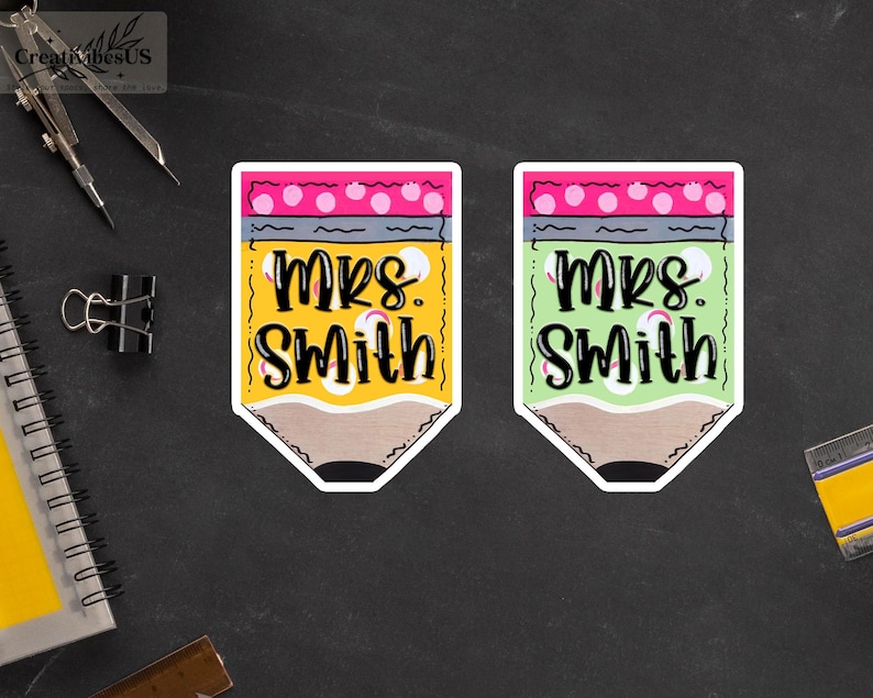 K&ouml;nnte beinhalten: Zwei bleistiftf&ouml;rmige Aufkleber, einer gelb und einer gr&uuml;n, beide mit dem Namen "Mrs. Smith" in schwarzer Schrift. Der gelbe Bleistift hat einen rosa Radiergummi mit wei&szlig;en Punkten, w&auml;hrend der gr&uuml;ne Bleistift einen rosa Radiergummi mit wei&szlig;en Punkten hat.