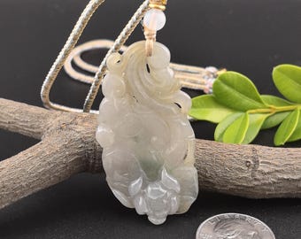 May include: A carved jade pendant necklace with a floral design. The pendant is a light green color and is hanging from a brown cord.