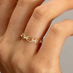 May include: A gold chain ring with small diamonds set into the links.