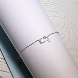 Puede incluir: Un brazalete de cadena de plata con un delicado dise&ntilde;o de constelaci&oacute;n. La constelaci&oacute;n est&aacute; hecha de peque&ntilde;as piedras brillantes.
