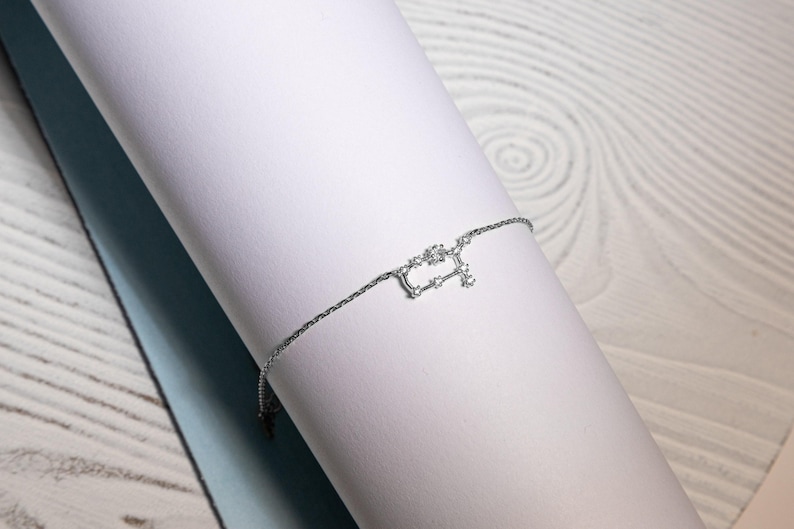 Puede incluir: Un brazalete de cadena de plata con un delicado dise&ntilde;o de constelaci&oacute;n. La constelaci&oacute;n est&aacute; hecha de peque&ntilde;as piedras brillantes.