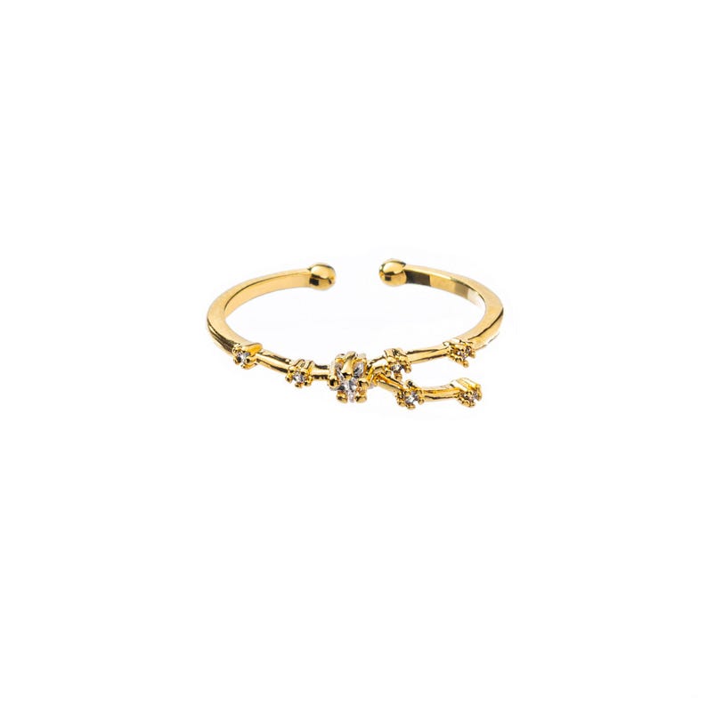 May include: Gold adjustable ring with a constellation design featuring small clear cubic zirconia stones.