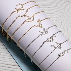 Puede incluir: Un conjunto de delicados collares de plata y oro con dise&ntilde;os de constelaciones. Cada collar tiene una constelaci&oacute;n diferente, con peque&ntilde;as piedras brillantes que representan las estrellas.