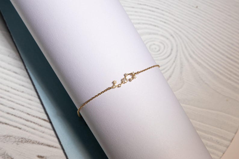 May include: A delicate gold chain bracelet with a constellation design featuring small sparkling stones.