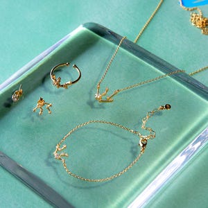 May include: A set of gold jewelry featuring a necklace, bracelet, ring, and earrings. Each piece is adorned with a delicate constellation design with small sparkling stones.