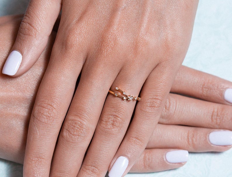 May include: A delicate gold ring with a constellation design featuring small sparkling diamonds.