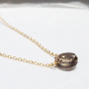 Puede incluir: Un collar de cadena dorada con un colgante de piedra preciosa marr&oacute;n en forma de l&aacute;grima.