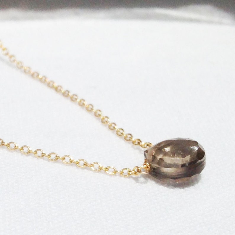 Puede incluir: Un collar de cadena dorada con un colgante de piedra preciosa marr&oacute;n en forma de l&aacute;grima.